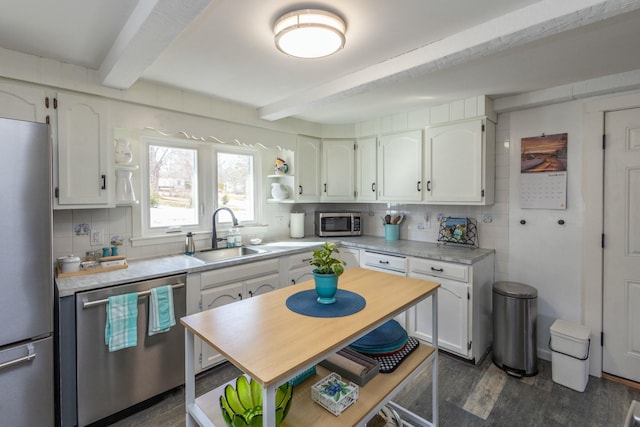 kitchen with a sink, beamed ceiling, stainless steel appliances, white cabinetry, and open shelves