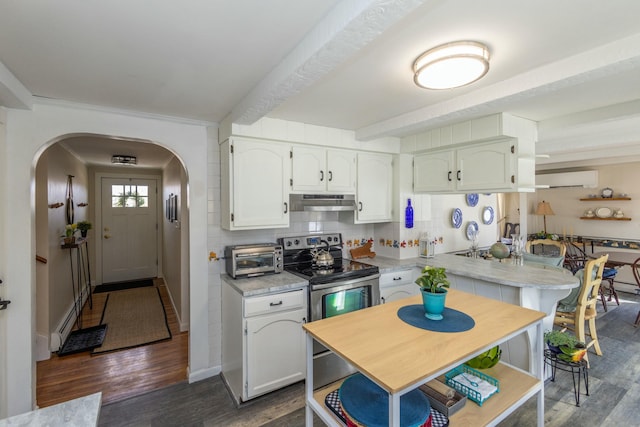 kitchen featuring dark wood-type flooring, under cabinet range hood, an AC wall unit, stainless steel electric range, and arched walkways