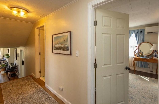 hall featuring baseboards, crown molding, and a wall unit AC