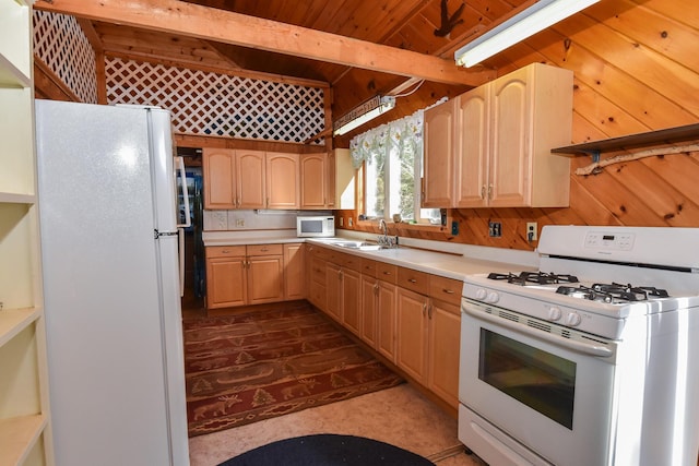 kitchen with light brown cabinetry, wood walls, white appliances, and light countertops