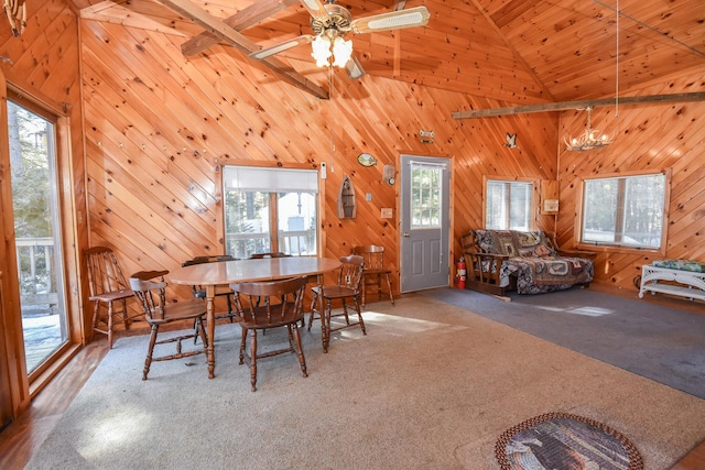 carpeted dining room featuring wooden walls, high vaulted ceiling, and a ceiling fan