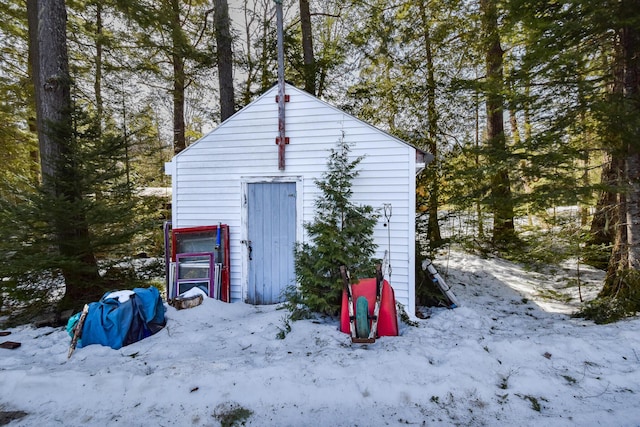 snow covered structure with an outbuilding