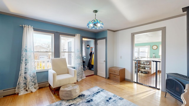 living area with baseboards, heating unit, ornamental molding, and hardwood / wood-style flooring