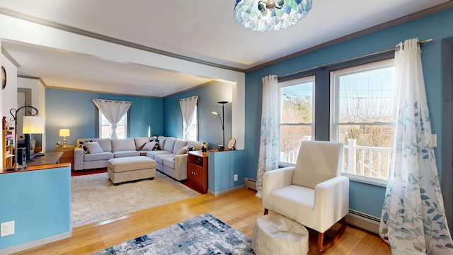 living room featuring light wood finished floors, baseboards, baseboard heating, and ornamental molding