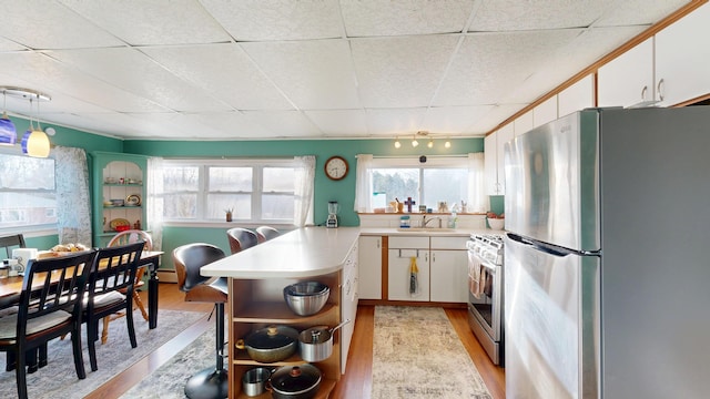 kitchen featuring light wood finished floors, light countertops, white gas range oven, freestanding refrigerator, and white cabinets