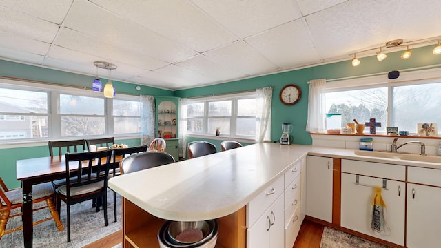 kitchen with a sink, plenty of natural light, light countertops, and open shelves