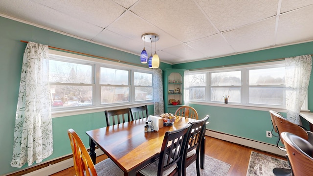 dining room featuring baseboard heating, wood finished floors, a paneled ceiling, and a baseboard radiator