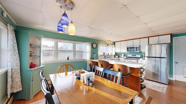 dining room featuring a baseboard heating unit, a paneled ceiling, and wood finished floors