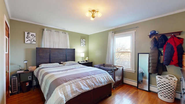 bedroom with ornamental molding, a baseboard heating unit, and wood finished floors