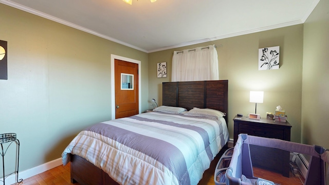 bedroom with baseboards, wood finished floors, and crown molding