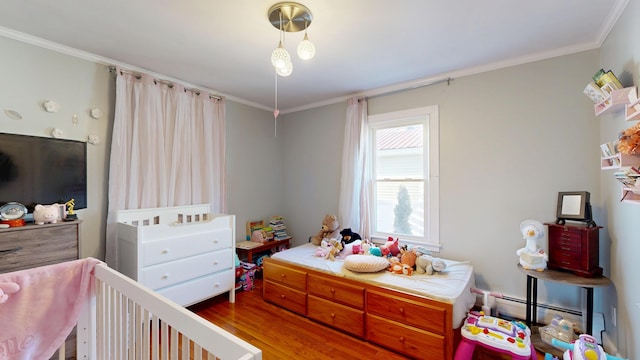 bedroom with a baseboard heating unit, wood finished floors, and crown molding