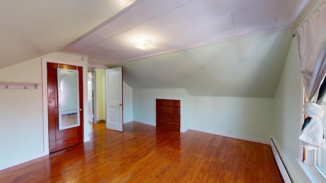 bonus room with a baseboard heating unit, vaulted ceiling, wood finished floors, and baseboards