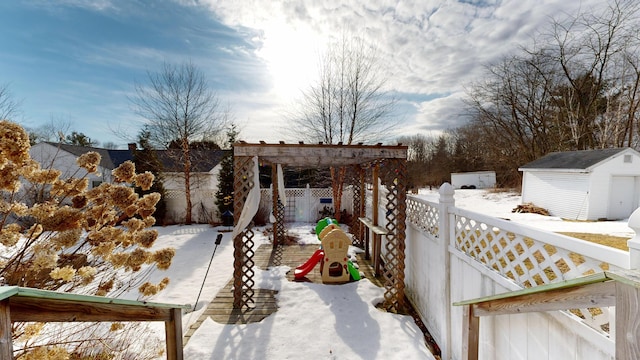 yard covered in snow with a storage shed, an outbuilding, and fence