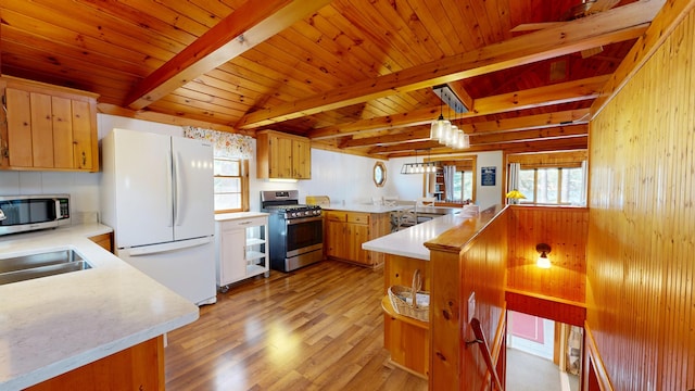 kitchen featuring light countertops, a peninsula, beam ceiling, and stainless steel appliances