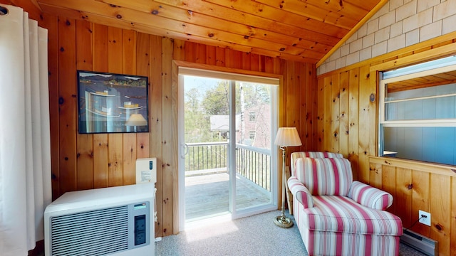 interior space with carpet floors, a baseboard heating unit, wood walls, and vaulted ceiling