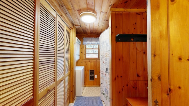 hallway with wood walls, wooden ceiling, and stacked washer / dryer