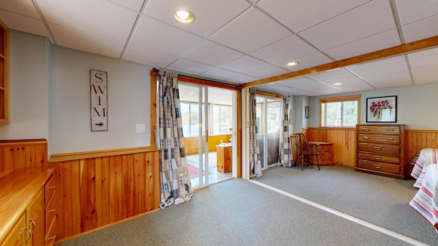 misc room featuring carpet floors, a drop ceiling, a wainscoted wall, and wooden walls