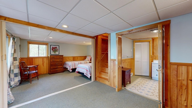 carpeted bedroom with wood walls and a wainscoted wall