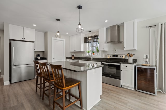 kitchen featuring light wood-style flooring, a sink, wine cooler, appliances with stainless steel finishes, and wall chimney range hood