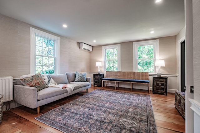 living area with recessed lighting, radiator, a wall mounted air conditioner, and wood-type flooring