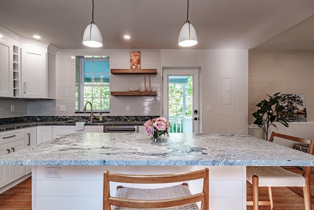 kitchen featuring open shelves, a sink, decorative backsplash, white cabinets, and a kitchen bar