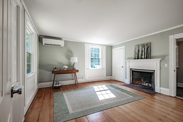 living room with crown molding, a fireplace, a wall mounted AC, and hardwood / wood-style floors