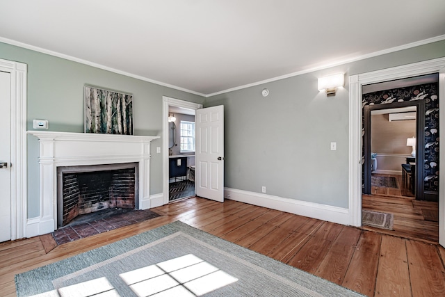 unfurnished living room with a fireplace with flush hearth, crown molding, baseboards, and hardwood / wood-style flooring