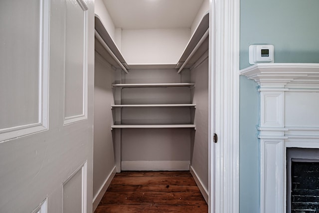 walk in closet featuring dark wood-type flooring and a fireplace