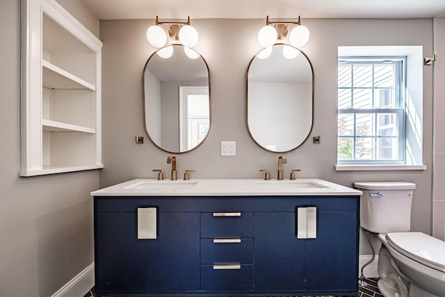 bathroom with double vanity, toilet, and a sink