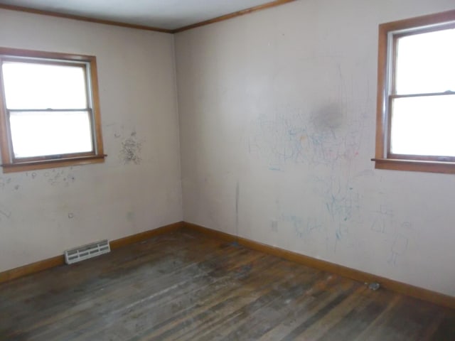 unfurnished room featuring visible vents, crown molding, baseboards, and wood finished floors