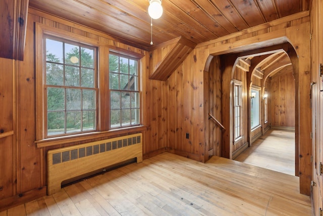 52 Main St, Sanford, ME 04083 - additional living space featuring arched walkways, wood walls, radiator heating unit, and hardwood / wood-style flooring