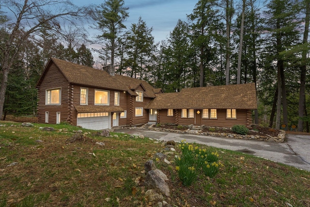52 Main St, Sanford, ME 04083 - view of front facade with log siding, a chimney, an attached garage, and aphalt driveway