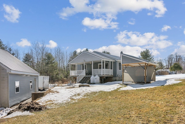 snow covered property featuring a porch and an outdoor structure