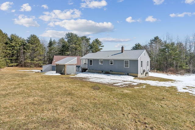 back of property with metal roof, a lawn, and a chimney