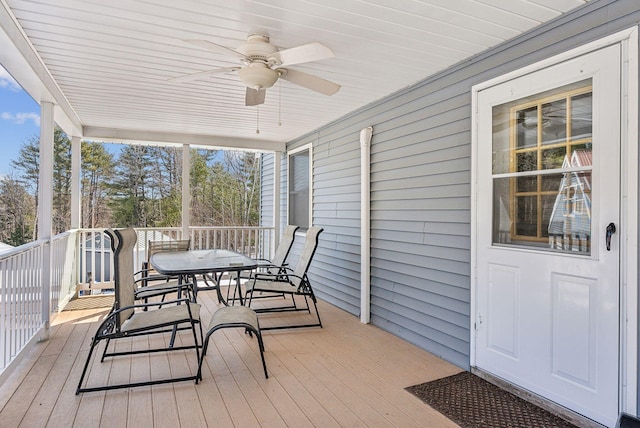 wooden terrace with outdoor dining space and a ceiling fan