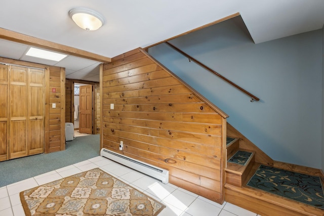 interior space featuring wooden walls, light tile patterned floors, light colored carpet, and baseboard heating