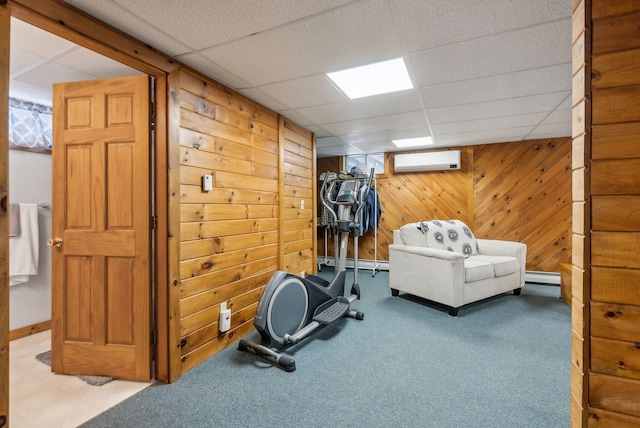 workout area featuring a drop ceiling, wood walls, a wall mounted air conditioner, carpet flooring, and baseboard heating