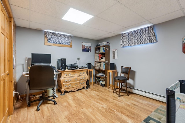 office featuring a drop ceiling, a baseboard heating unit, and wood finished floors