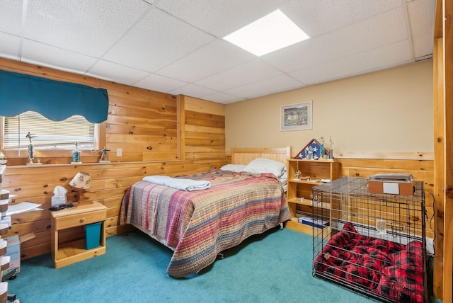 bedroom with a drop ceiling, carpet, and wooden walls