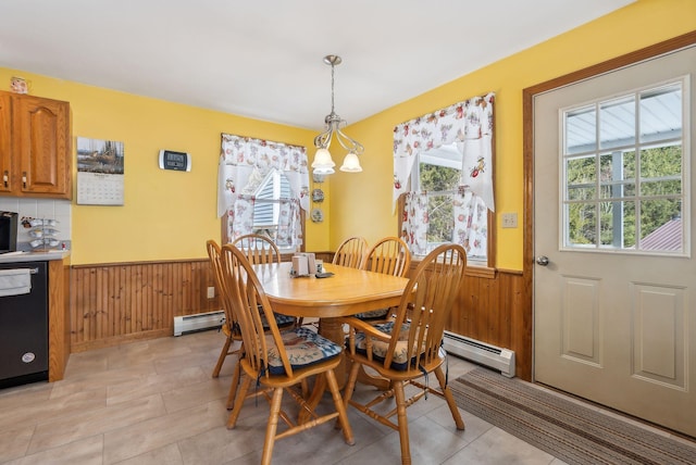 dining area with a wainscoted wall, wood walls, a baseboard heating unit, and an inviting chandelier