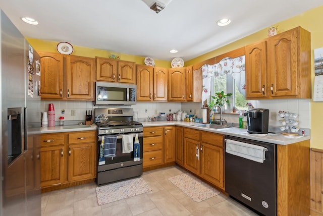 kitchen featuring a sink, appliances with stainless steel finishes, brown cabinetry, and light countertops