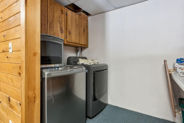 clothes washing area with washing machine and dryer, cabinet space, and carpet