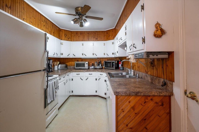 kitchen featuring dark countertops, white cabinets, white appliances, a ceiling fan, and a sink