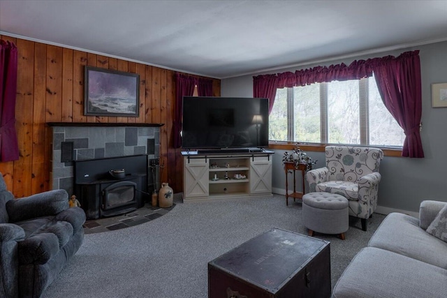 living area featuring a wood stove, baseboards, carpet floors, and ornamental molding