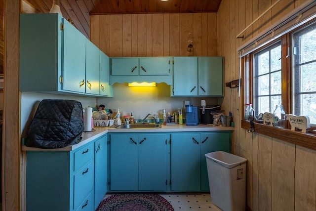 kitchen with wooden walls, plenty of natural light, light countertops, and a sink