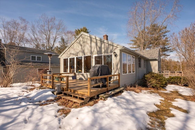 snow covered house with a deck and a chimney