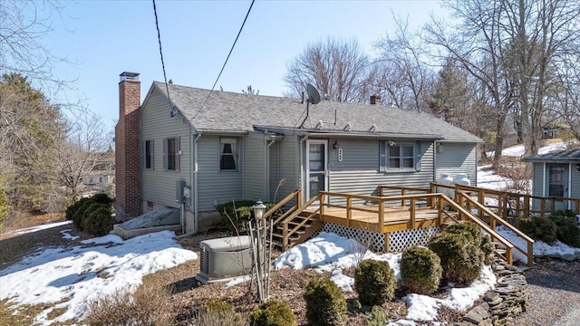 view of front of house with a chimney, a deck, and a shingled roof