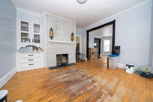 unfurnished living room featuring hardwood / wood-style flooring, baseboards, and ornamental molding