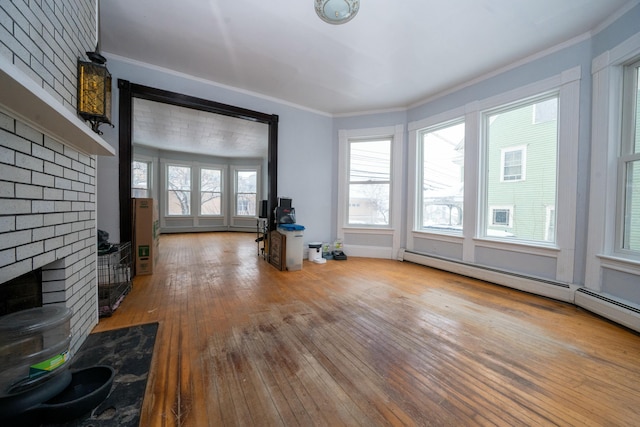 unfurnished living room featuring a fireplace, hardwood / wood-style flooring, crown molding, and a baseboard radiator