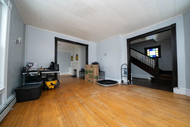 living room with stairs, hardwood / wood-style flooring, baseboards, and baseboard heating